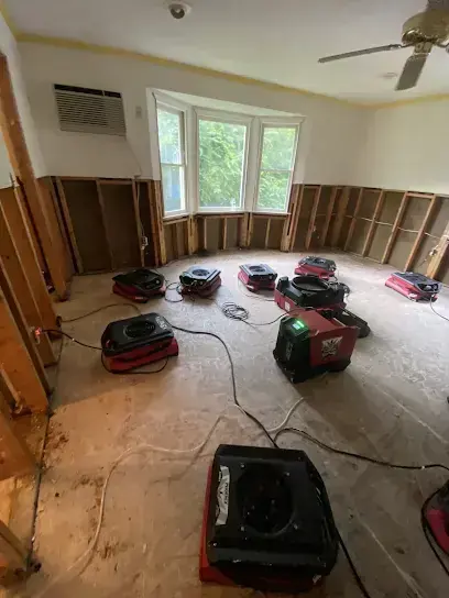 Room with flood-cut walls and red air movers drying the floor during a Goose Creek dry-out