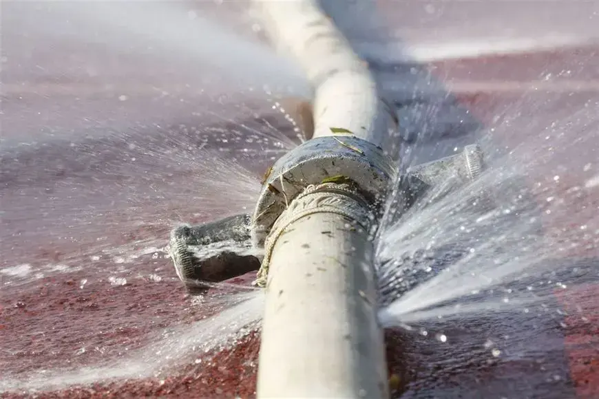 Water spraying from a broken white supply pipe fitting, burst pipe water damage in Goose Creek