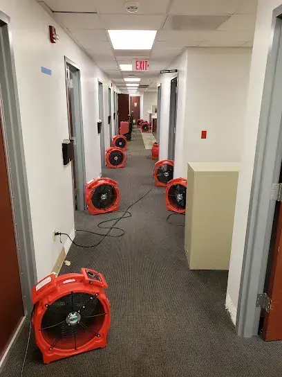 Row of air movers drying the carpet of a long office hallway, commercial water damage in Goose Creek