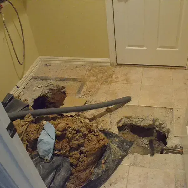 Tile floor and concrete slab broken open beside a doorway to reach a leaking pipe, slab leak water damage in Goose Creek